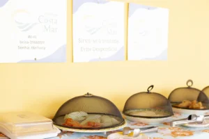 Buffet de café da manhã organizado com protetores de alimentos na Pousada Costa do Mar