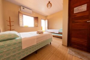 Quarto arejado com ar-condicionado e roupas de cama limpas em tons de azul e branco.