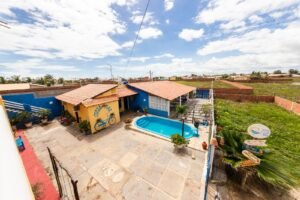 Vista aérea mostrando o Hospedagem em Luis Correia, prédio amarelo, área da piscina e proximidade com a natureza